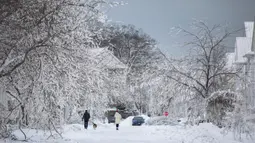 Orang-orang berjalan menyusuri jalan bersalju menyusul badai musim dingin yang melanda sebagian besar Ontario di Fort Erie, Ontario, Kanada, 27 Desember 2022. Kondisi kian buruk dengan suhu yang hampir mencapai minus 45 derajat celcius. (Nick Iwanyshyn/The Canadian Press via AP)