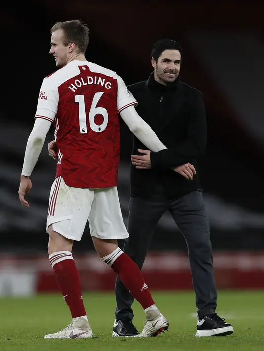 Pelatih Arsenal, Mikel Arteta (kanan) memberi selamat kepada bek Rob Holding usai pertandingan melawan Chelsea pada lanjutan Liga Inggris di Stadion Emirates di London, Minggu (27/12/2020). Mikel Arteta berharap, kemenangan ini menjadi titik kebangkitan timnya. (AFP/Pool/Adrian Dennis)