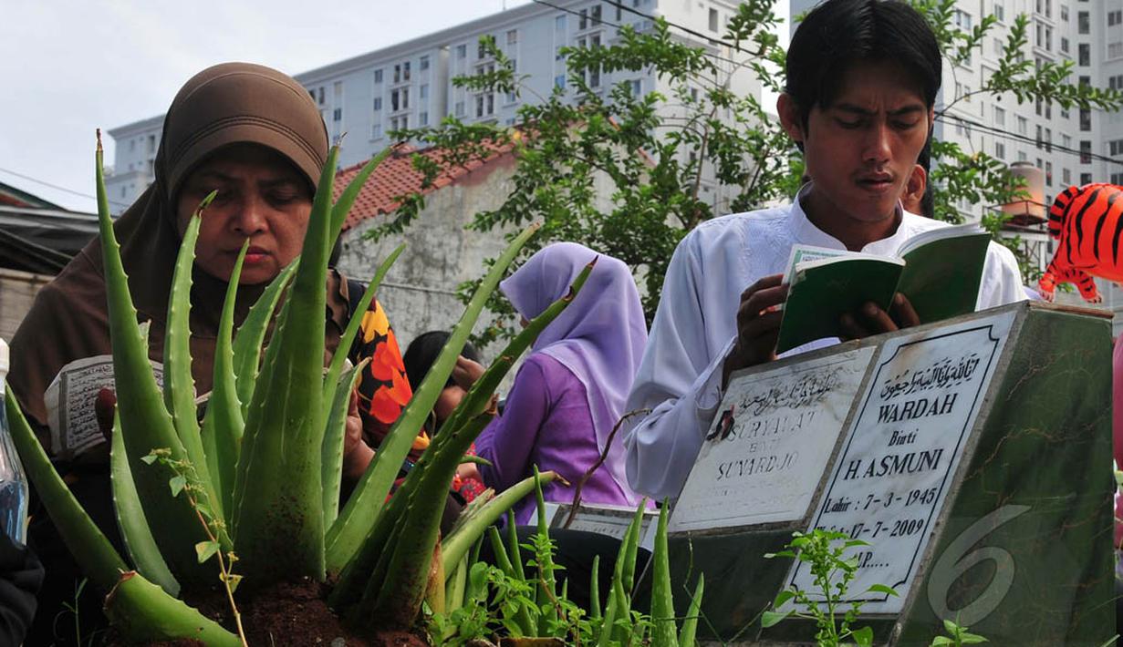 Sebuah keluarga melakukan ziarah dan doa di makam kerabatnya di TPU Karet Bivak, Jakarta, Senin (28/7/14). (Liputan6.com/Johan Tallo)