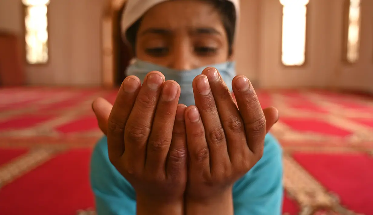 Seorang anak yatim Muslim mengenakan masker berdoa sambil menjaga jarak sosial di dalam pusat panti asuhan selama bulan suci Ramadan di Srinagar (11/5/2020). (AFP/Tauseff Mustafa)