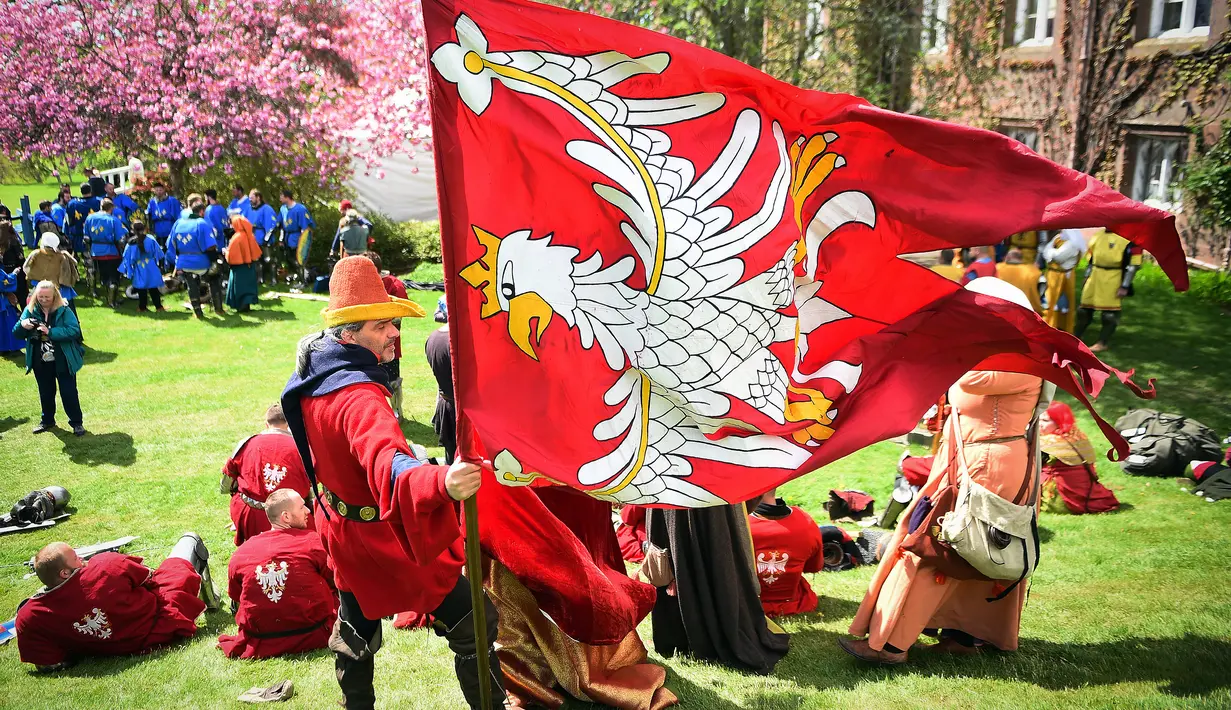 Seorang peserta memegang bendera timnya saat mengikuti kompetisi IMCF di Scone Palace, Perthshire, Skotlandia (10/5). Mereka bergaya dan menggunakan senjata yang dulu digunakan para kesatria untuk bertempur.  (AFP/Andy Buchanan)