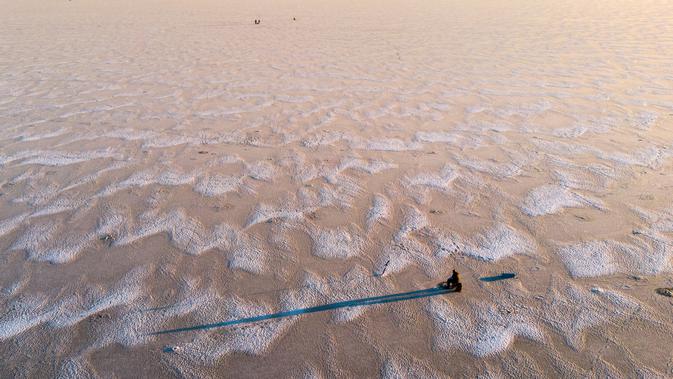 Seorang pria sedang memancing di tengah Laut Bothnia yang membeku di dekat Vaasa, Finlandia, 28 Desember 2018. Sebelum memancing, mereka membuat lubang menggunakan bor untuk memberikan umpannya kepada ikan buruan. (OLIVIER MORIN / AFP)