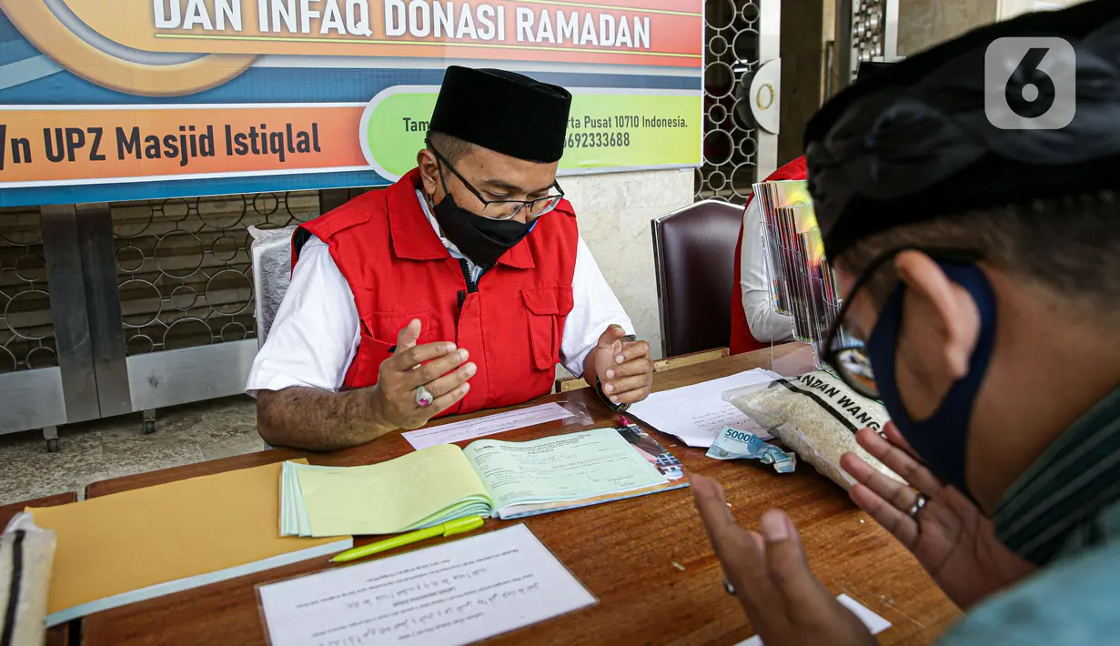 Amil zakat mendoakan umat muslim yang membayar zakat fitrah di Masjid Istiqlal, Jakarta, Jumat (7/5/2021). Panitia Zakat Masjid Istiqlal mulai membuka layanan pembayaran zakat fitrah dengan pembayaran senilai Rp 50 ribu atau 3,5 liter beras. (Liputan6.com/Faizal Fanani)