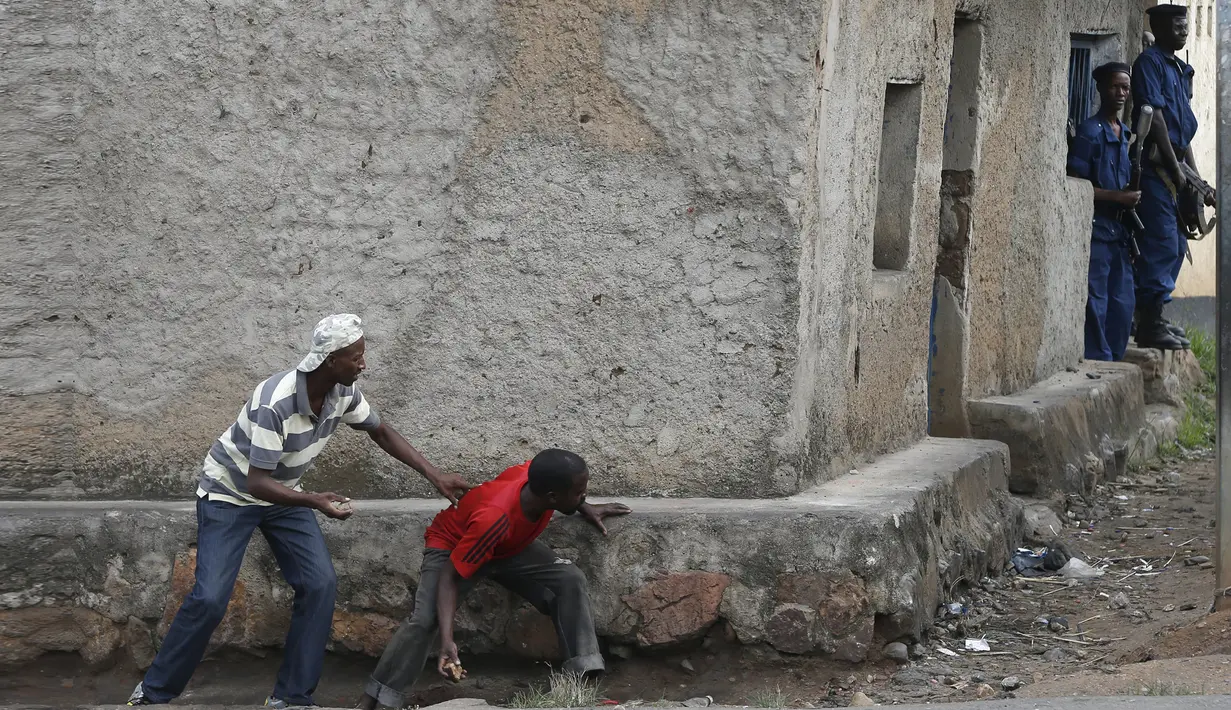 Pengunjuk rasa sembunyi dibalik dinding dengan membawa batu bersiap menyerang petugas di Bujumbura, Burundi, (20/5/2015). Kerusuhan dipicu protes terhadap Presiden Burundi Pierre Nkurunziza untuk upayanya menambah masa jabatan. (REUTERS/Goran Tomasevic)