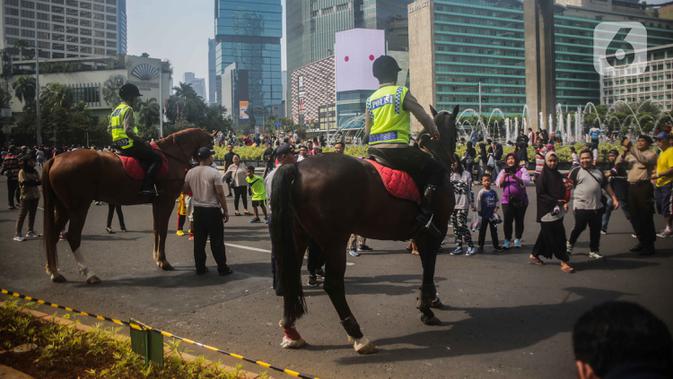 Sejumlah warga berfoto dengan polisi berkuda dari Direktorat Polisi Satwa Mabes Polri di kawasan Bundaran HI, Jakarta, Minggu (17/11/2019). Polisi berkuda tersebut khusus ditugaskan mengawasi keamanan CFD serta memperkenalkan kepada warga. (Liputan6.com/Faizal Fanani)