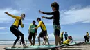 Orang-orang belajar berselancar di pantai Kuta, Bali, 8 Desember 2023. (SONNY TUMBELAKA/AFP)