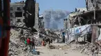 Asap mengepul ke arah utara menjadi latar ketika warga Palestina bergerak melalui Jabalia meninggalkan Jalur Gaza utara menuju Kota Gaza pada 19 Mei 2025. (Bashar TALEB/AFP)