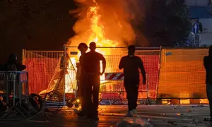 Api berkobar setelah bentrokan antara polisi dan demonstran kelompok Italia in Piazza di depan Katedral Milan, Italia, pada Sabtu (17/10/2026). (Dok. Stefano Porta/LaPresse via AP)