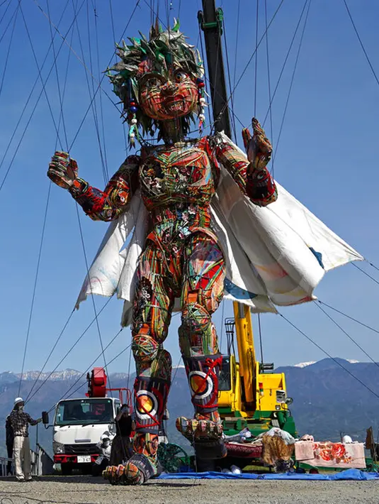 Pekerja mengatur boneka raksasa MOCCO saat sesi latihan khusus di Takamori, Prefektur Nagano, Jepang, Jumat (23/4/2021). Penyelenggara Olimpiade Tokyo menciptakan boneka setinggi sekitar 10 meter untuk melambangkan semangat masyarakat yang terdampak gempa dan tsunami 2011 lalu. (AP Photo/Koji Ueda)