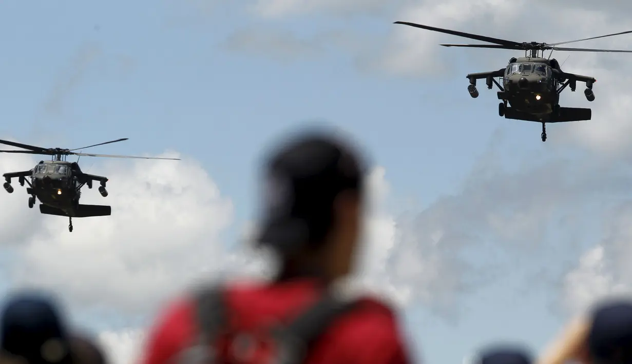 Sejumlah warga menyaksikan aksi manuver helikopter Blackhawk-Arpia di F-Air Colombia 2015 di F-Air Colombia 2015 di Rionegro, Kolombia (9/7/2015). Heli ini sering digunakan untuk misi-misi pasukan khusus. (REUTERS/Fredy Builes)