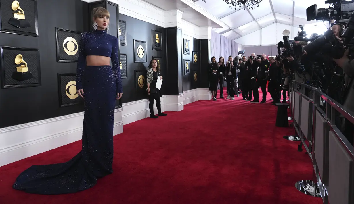 Taylor Swift berpose untuk fotografer di karpet merah ajang Grammy Awards 2023 di Crypto.com Arena, Los Angeles, AS, Senin (6/2/2023) pagi waktu Indonesia. Melansir dari ET Online, para penggemar pun dengan cepat menelusuri bahwa gaun tersebut  memiliki warna yang sama dengan gaun GRAMMY era Fearless-nya dan seperti penampilan GRAMMY 1989-nya, itu adalah pakaian dua potong (two-piece). (Photo by Jordan Strauss/Invision/AP)