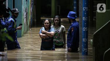 Warga berjalan melintasi banjir di kawasan Kampung Melayu, Jakarta, Senin (8/11/2021). Banjir akibat luapan Kali Ciliwung tersebut merendam pemukiman setinggi 60 cm sejak 7 November 2021 sore. (Liputan6.com/Faizal Fanani)