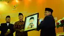 Suryadharma Ali mendapat karikatur dirinya usai membuka Rapimnas LDII di Balai Kartini, Jakarta, Selasa (13/4/2014) (Liputan6.com/Andrian M Tunay).