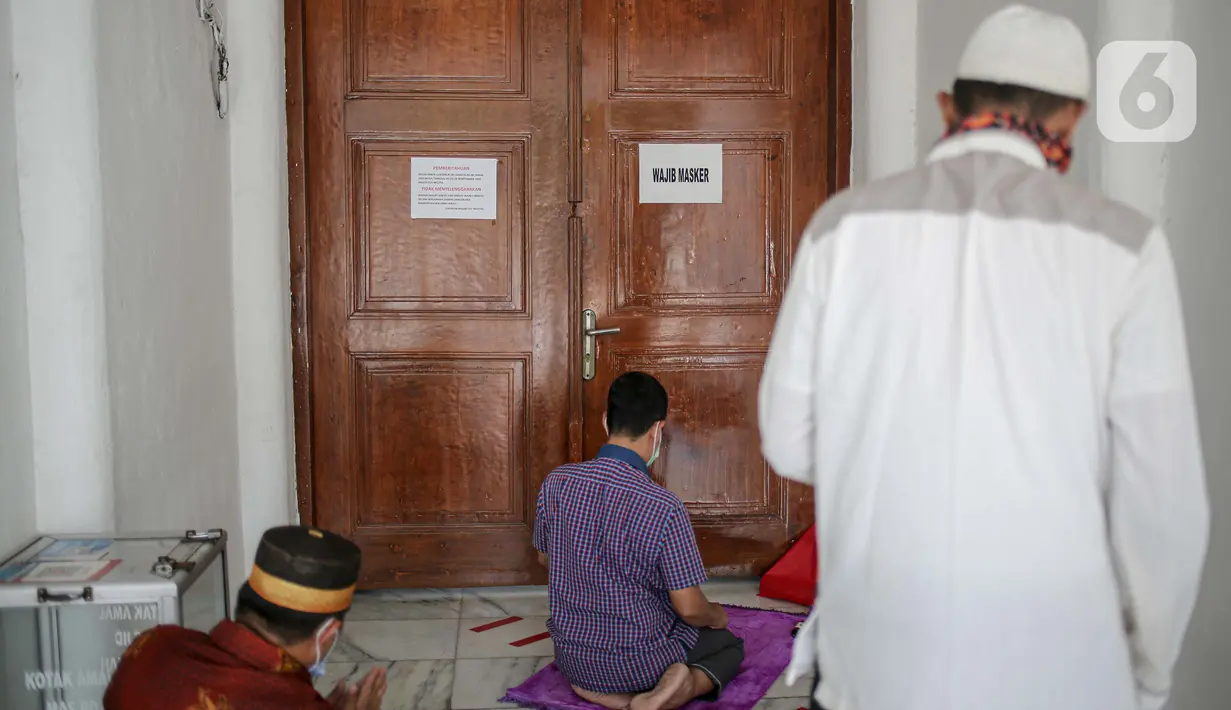 Sejumlah warga melaksanakan salat zuhur di halaman depan Masjid Cut Meutia, Jakarta, Jumat (18/9/2020). Pemprov DKI Jakarta kembali meniadakan kegiatan ibadah salat Jumat dan salat lima waktu berjemaah di semua Masjid Raya selama PSBB. (Liputan6.com/Faizal Fanani)