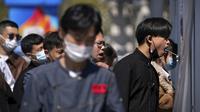 Para pekerja yang mengenakan masker antre mengambil swab tenggorokan di tempat pengujian virus corona di Beijing, Minggu (3/4/2022). Kasus COVID-19 di kota terbesar di China, Shanghai, masih meningkat saat jutaan orang tetap terisolasi di rumah di bawah lockdown besar-besaran. (AP Photo/Andy Wong)