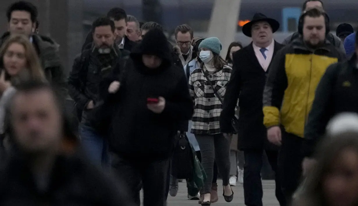 Pekerja berjalan di atas Jembatan London menuju distrik keuangan Kota London selama jam sibuk pagi hari, di London, Senin (24/1/2022). Pemerintah Inggris telah meminta orang-orang untuk kembali bekerja di kantor mulai Senin karena mereka melonggarkan pembatasan corona COVID-19. (AP Photo/Matt Dunham