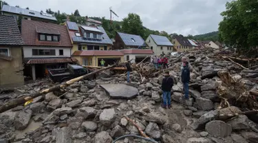 Warga mengamati jalan rusak menyusul bencana banjir dahsyat di Braunsbach, Senin (30/5). Empat orang tewas dan beberapa luka-luka akibat banjir melanda wilayah barat Jerman setelah hujan deras terjadi sepanjang Ahad (29/5). (Marijan Murat/dpa/AFP)