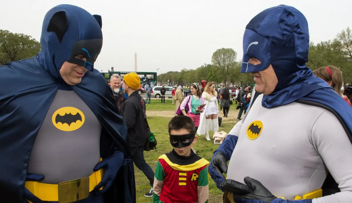 Dua pria dewasa bertopeng Batman ditemani Robin cilik saat diacara memecahkan rekor dunia untuk karakter buku komik terbanyak dunia, Washington DC, (18/4/2014) (AFP Photo/Paul J. Ricards).