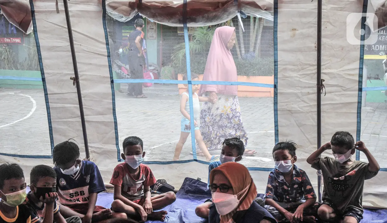 Anak-anak mendengarkan dongeng yang dikisahkan petugas di tenda pengungsian di SDN 09 Kebon Kosong, Kemayoran, Jakarta, Selasa (31/8/2021). Kegiatan bertujuan menghilangkan trauma atau rasa takut serta kebosanan anak-anak korban kebakaran saat berada di pengungsian. (merdeka.com/Iqbal S. Nugroho)