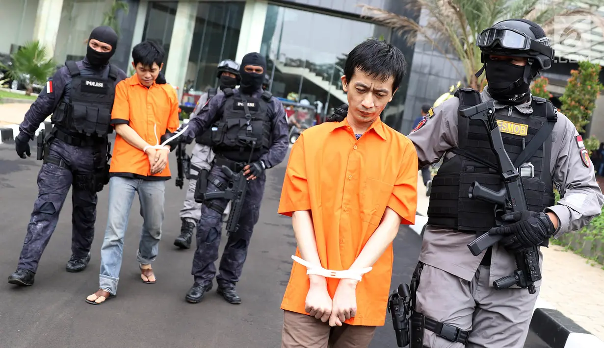Petugas kepolisian menggiring para pelaku penyelundupan narkoba dari Malaysia di Polda Metro Jaya, Jakarta, Senin (12/2). Polisi mengamankan barang bukti berupa 239,785 kg sabu dan 30.000 butir ekstasi. (Liputan6.com/Immanuel Antonius)