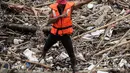 Petugas kebersihan berpose menggunakan topeng Spiderman membersihkan sampah yang menumpuk di Pintu Air Manggarai, Jakarta, Senin (12/11). (Liputan6.com/Fery Pradolo)