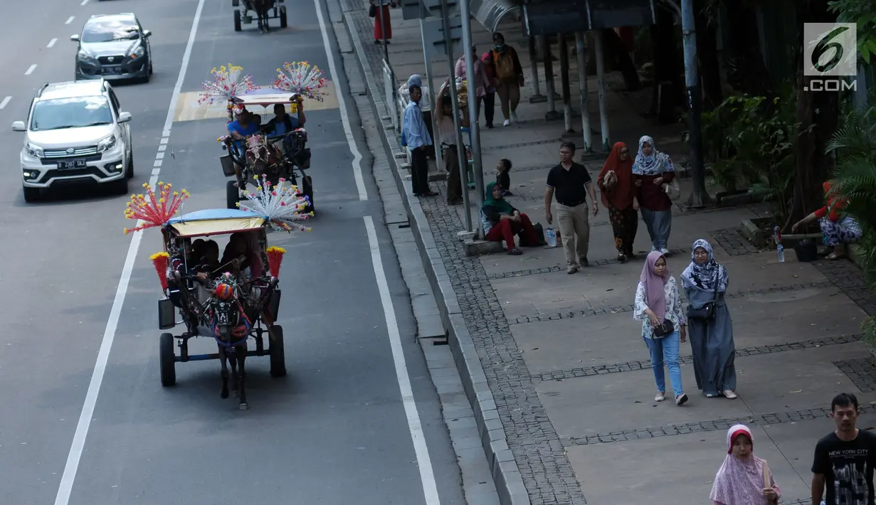 Delman hias membawa penumpang melintasi Jalan Medan Merdeka Barat, Jakarta, Selasa (19/6). Masa libur Lebaran 2018 dimanfaatkan sejumlah warga untuk berwisata di sekitar Monumen Nasional dengan menaiki delman hias. (Liputan6.com/Helmi Fithriansyah)