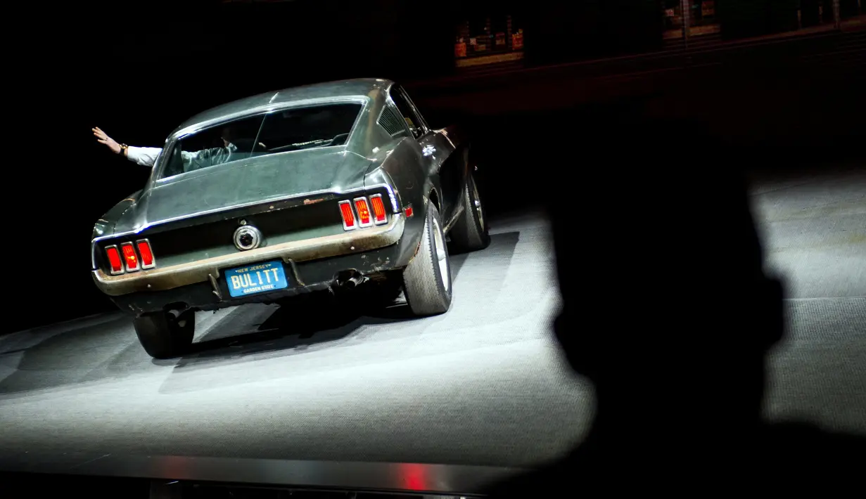 Sean Kiernan melambaikan tangannya saat menaiki mobil asli yang digunakan dalam pembuatan film "Bullitt" di North American International Auto Show, Detroit (14/1). (AP Foto / Carlos Osorio)