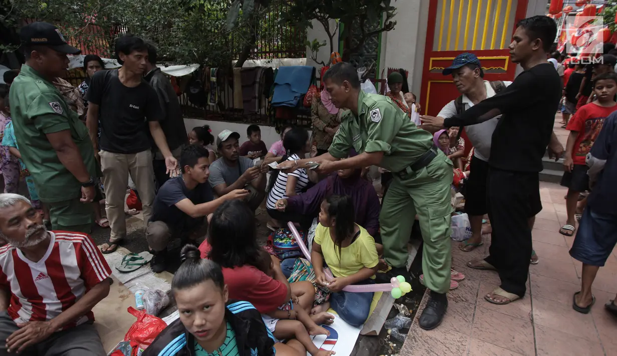 Petugas membagikan angpau kepada pengemis di Wihara Dharma Bhakti, Petak Sembilan, Jakarta Barat, Jumat (16/2). Dalam perayaan Tahun Baru Imlek, pembagian Angpao ini biasa dilakukan warga Tionghoa untuk berbagi rezeki. (Liputan6.com/Arya Manggala)