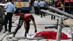 Polisi menutupi tubuh jenazah korban tewas akibat sebuah bus menabrak halte yang penuh penumpang di distrik Dikimevi, Ankara, Turki, Kamis (1/10/2015). 12 orang tewas akibat bus kehilangan kendali karena mengalami rem blong. (AFP PHOTO/ADEM ALTAN)