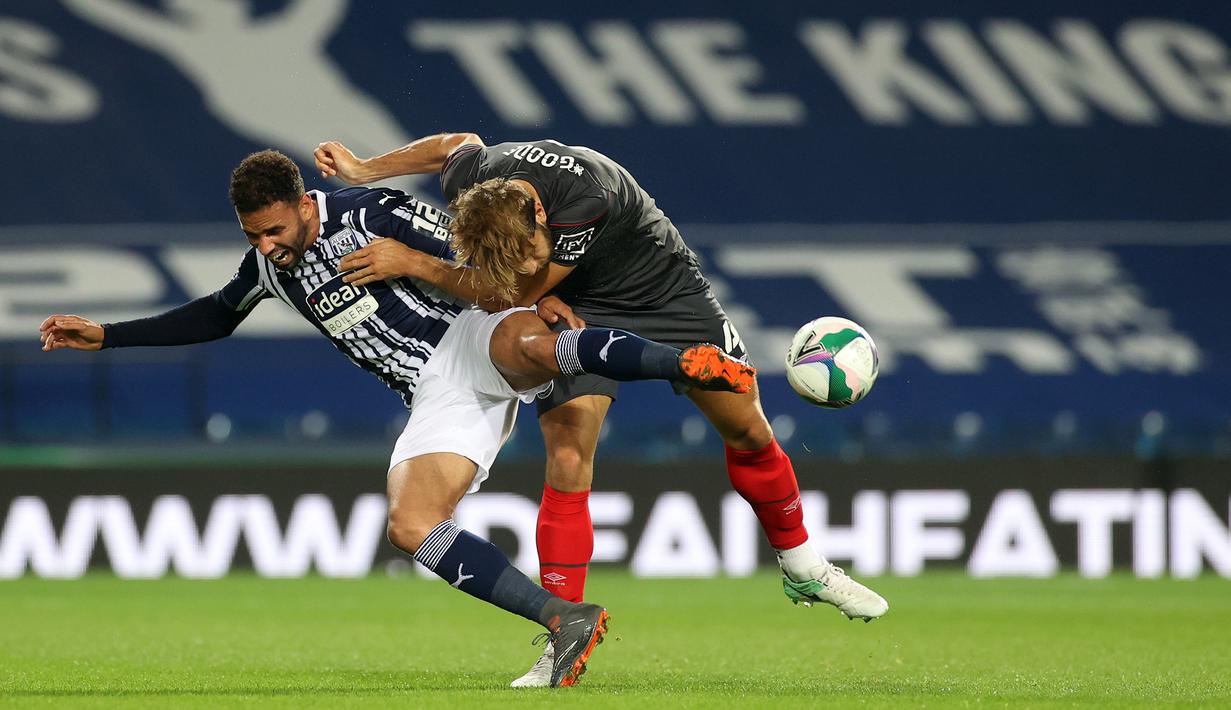 Striker West Brom, Robson-Kanu, berebut bola dengan bek Brentford, Charlie Goode, dalam laga Piala Inggris di venue The Hawthorns, Rabu (23/9/2020) dini hari WIB. West Brom kalah 6-7 atas Brentford lewat adu penalti. (AFP/Carl Recine/pool)