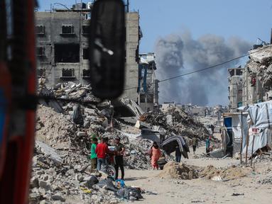 Asap mengepul ke arah utara menjadi latar ketika warga Palestina bergerak melalui Jabalia meninggalkan Jalur Gaza utara menuju Kota Gaza pada 19 Mei 2025. (Bashar TALEB/AFP)