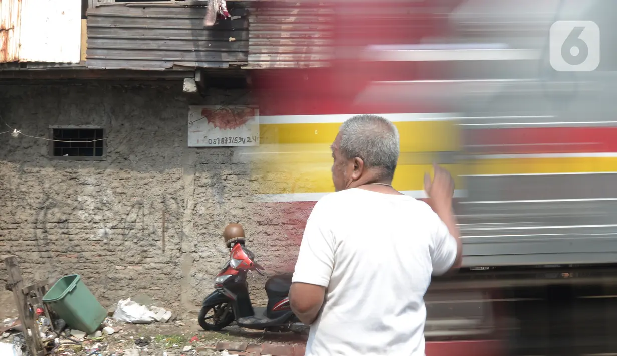 Penjaga perlintasan kereta api tanpa palang pintu, Wandi, berdiri tepat di samping perlintasan di Kawasan Petamburan, Jakarta, Jumat (4/6/2021). Di usianya yang tidak lagi muda, Pak Wandi tetap ada di mata pengendara dan pejalan kaki yang melintas di antara pemukiman warga. (merdeka.com/Imam Buhori)