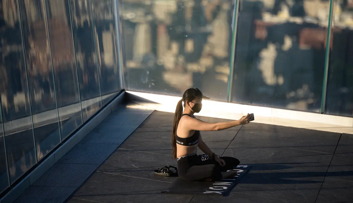 Praktisi yoga menghadiri kelas di Edge Observation Deck, Manhattan, New York, Amerika Serikat, Kamis (17/6/2021). Di tempat ini, para praktisi bisa berlatih yoga sambil menghadap cakrawala. (Ed JONES/AFP)