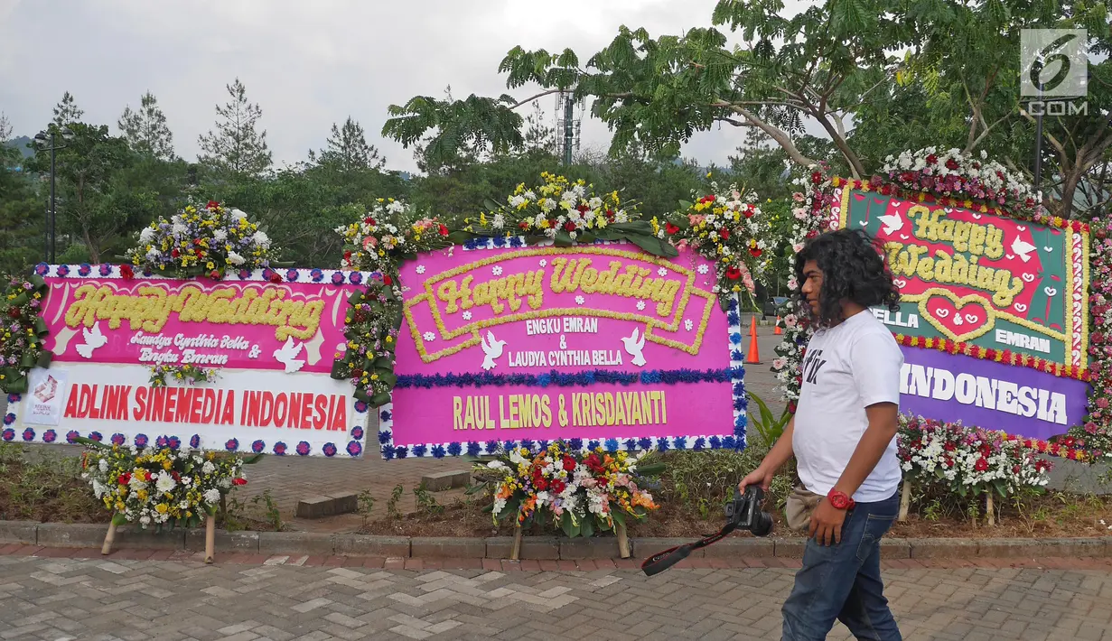 Pejalan kaki melintasi karangan bunga ucapan selamat untuk Laudya Cynthia Bella dan Engku Emran di lokasi resepsi pernikahan kawasan Dago, Bandung, Minggu (8/10). Acara resepsi akan digelar secara tertutup dari awak media. (Liputan6.com/Herman Zakharia)