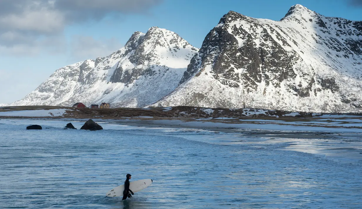 Peselancar wanita usai berselancar di pantai bersalju Flackstad di Kepulauan Lofoten, Lingkar Arktik, pada 13 Maret 2016. Suhu dingin memberikan sensasi tersendiri bagi peselancar terlepas dari cuaca yang sangat tidak stabil. (AFP/Olivier Morin)