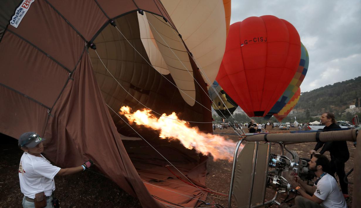 Peserta mempersiapkan balon udaranya sebelum mengikuti Festival Balon Udara Gilboa di dekat Kibbutz Ein Harod, Lembah Jizreel, Israel (4/8). Festival balon udara ini menjadi tontonan menarik bagi warga sekitar dan wisatawan. (AFP Photo/Manahem Kahana)