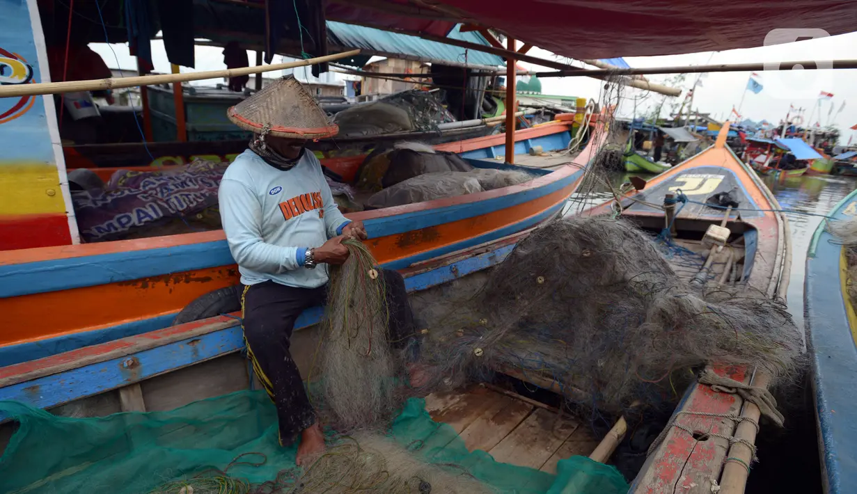 Seorang nelayan memperbaiki jaring di atas perahu yang bersandar di Dermaga Muara Angke, Jakarta, Selasa (19/2021). Memasuki musim pancaroba ditambah kencangnya angin, nelayan mengatakan hasil tangkapan ikan menjadi tidak menentu. (merdeka.com/Imam Buhori)