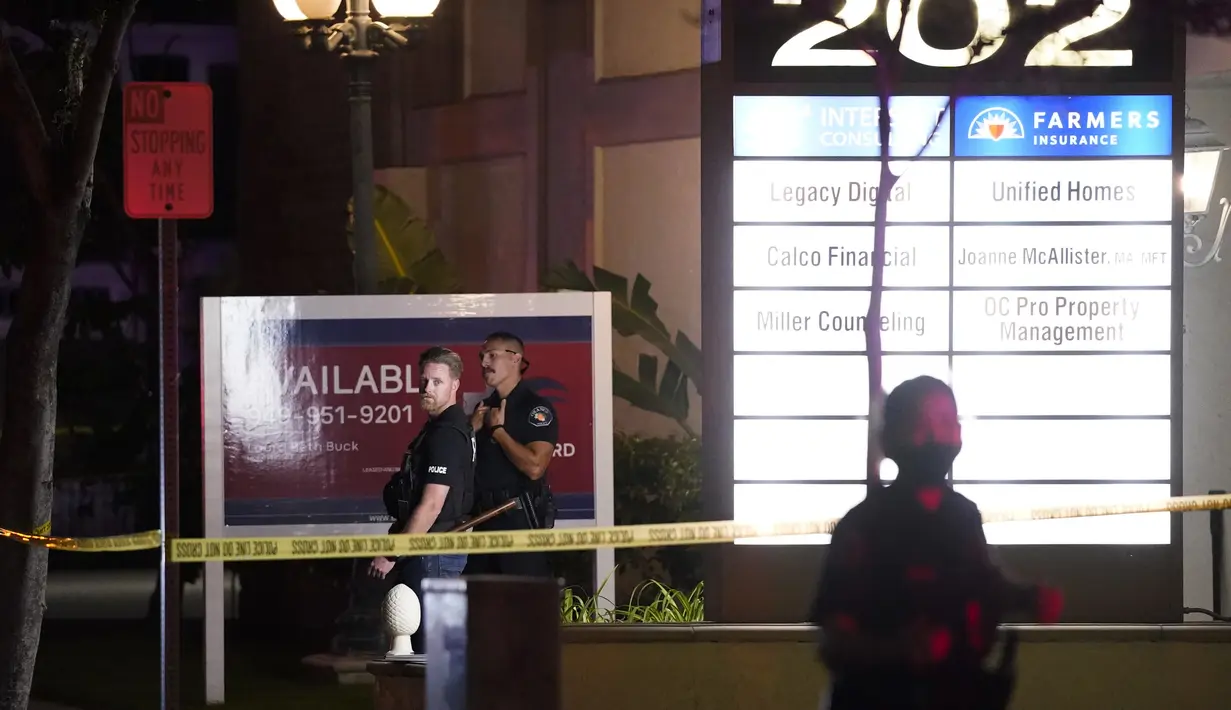 Petugas polisi berdiri di luar gedung bisnis tempat penembakan terjadi di Orange, California California (31/3/2021).  Pihak berwenang mengatakan bahwa empat orang, termasuk seorang anak, tewas dalam penembakan tersebut. (AP Photo/Jae C. Hong)