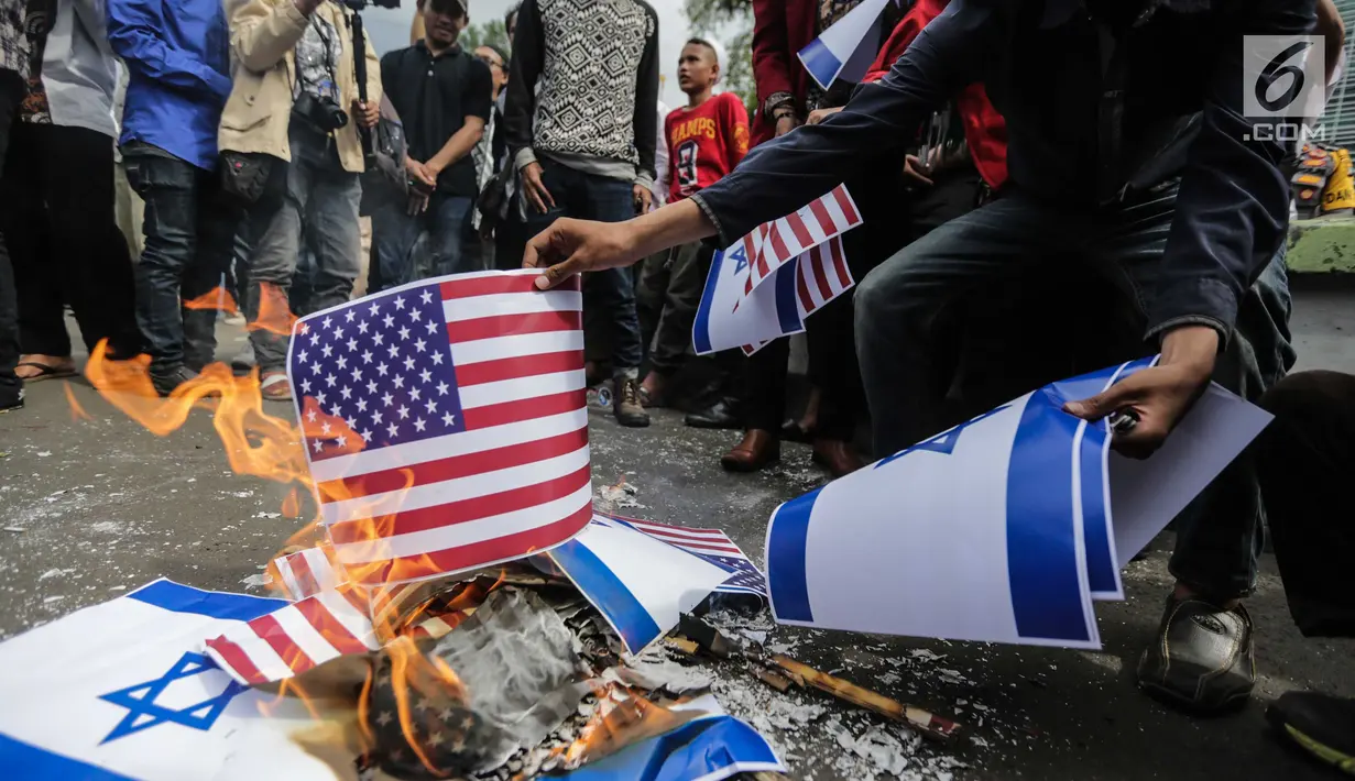 Massa membakar bendera Amerika Serikat dan Israel dalam Aksi Bela Palestina di depan Kedubes AS, Jakarta, Jumat (15/12). Mereka juga mendesak pemerintah Indonesia menghentikan kerja sama diplomatik dengan Amerika Serikat. (Liputan6.com/Faizal Fanani)