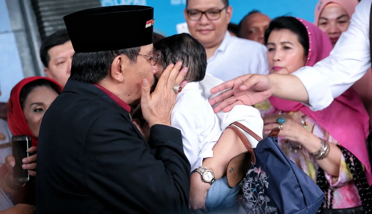 Baru keluar, ia langsung mengambil alih cucunya yang digendong oleh istrinya, Ida Laksmiwati yang mengenakan baju dan krudung merah. (Adrian Putra/Bintang.com)