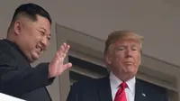Pemimpin Korea Utara Kim Jong-un (kiri) melambaikan tangan saat tampil bersama Presiden AS Donald Trump di balkon Hotel Capella, Pulau Sentosa, Singapura, Selasa (12/6). Pertemuan keduanya membicarakan masalah denuklirisasi Korea Utara. (SAUL LOEB/AFP)