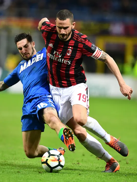 Bek AC Milan, Leonardo Bonucci berebut bola dengan pemain Sassuolo, Matteo Politano pada laga pekan ke-31 Serie A di San Siro, Minggu (8/4). Menjamu Sassuolo, AC Milan gagal meraih kemenangan usai hanya bermain imbang 1-1. (AP/Antonio Calanni)