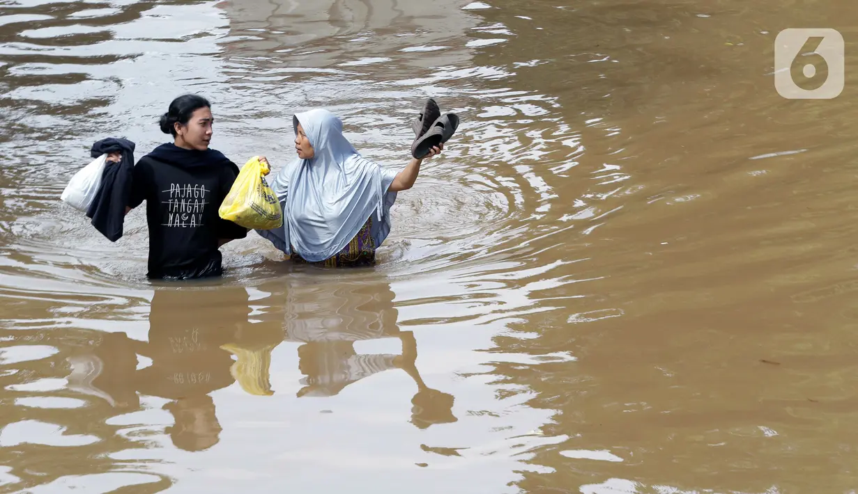Warga berjalan menyusuri banjir yang menggenangi sebagian ruas Jalan Warung Buncit Raya, Jakarta, Sabtu (20/2/2021). Hujan yang mengguyur Jakarta sejak Jumat (19/2) membuat arus lalu lintas sejumlah jalan di Jakarta lumpuh akibat terendam banjir. (Liputan6.com/Helmi Fithriansyah)