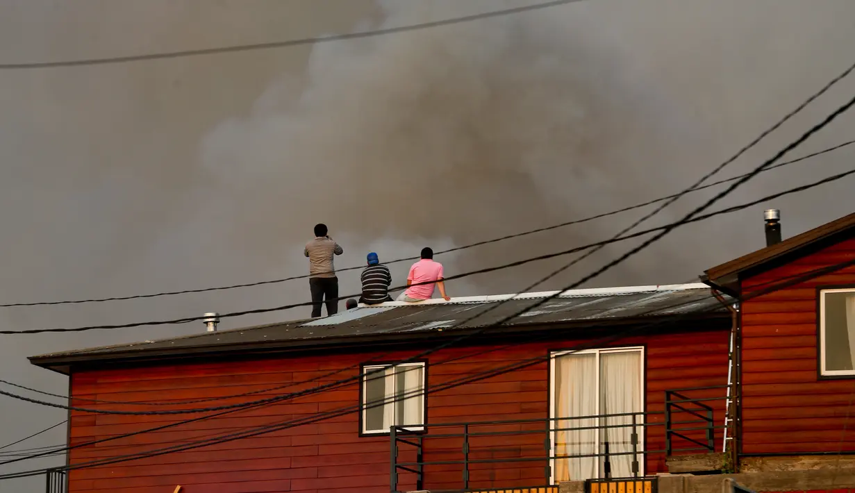 Sejumlah warga melihat kepulan asap di atas rumah mereka di kawasan Dichato Chili, Senin (30/1). Kekeringan, angin kencang dan suhu tinggi telah memicu serangkaian kebakaran di Central Chile sejak November 2016. (AP Photo / Esteban Felix)
