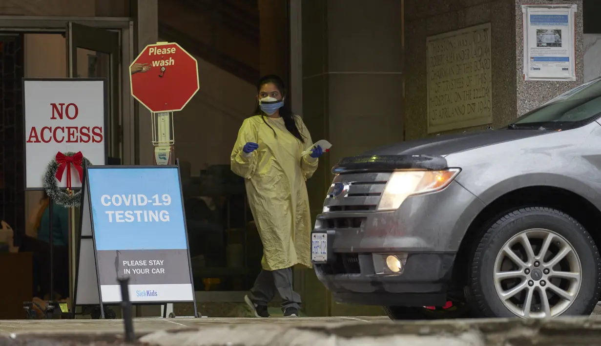 Seorang petugas kesehatan The Hospital for Sick Children di Toronto, Ontario, bertugas di pusat pengujian Covid-19 drive-thru, Rabu (5/1/2022). Salah satu provinsi di Kanada itu memberlakukan pembatasan baru mulai hari ini untuk memperlambat penyebaran Covid-19 varian Omicron. (Geoff Robins/AFP)