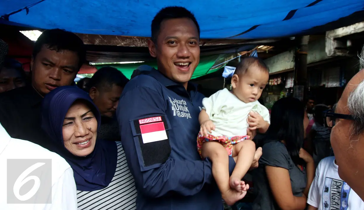 Calon Gubernur DKI Jakarta Agus Harimurti Yudhoyono menggendong seorang balita saat mengunjungi Pasar Paseban Jakarta Pusat, Jumat (11/11). Agus disambut hangat pedagang maupun pengunjung pasar tersebut. (Liputan6.com/Gempur M Surya)