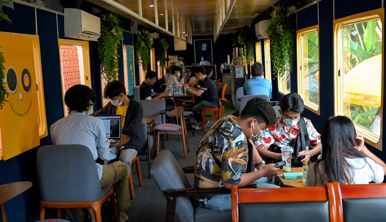 Foto yang diambil pada 5 Juni 2021 menunjukkan orang-orang duduk di dalam sebuah kafe, dari gerbong kereta, di stasiun kereta api di Phnom Penh. Gerbong kereta diubah menjadi kafe setelah selama pandemi corona sebagian besar perjalanan kereta api di Kamboja dihentikan. (TANG CHHIN Sothy/AFP)