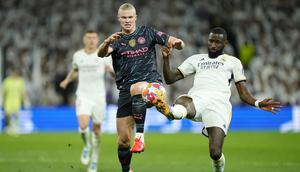 Striker Manchester City, Erling Haaland (kiri) berebut bola dengan bek Real Madrid, Antonio Rudiger pada laga leg pertama babak perempatfinal Liga Champions 2023/2024 di Santiago Bernabeu Stadium, Selasa (9/4/2024) malam. (AP Photo/Manu Fernandez)