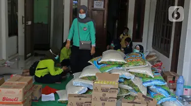 Warga mengemas bantuan bahan pokok untuk pasien positif Covid-19 di RT03/RW03, Kelurahan Cilangkap, Jakarta, Jumat (21/5/2021). Sebanyak 25 paket bahan pokok dari bantuan Dinas Sosial DKI Jakarta dan swadaya warga setempat diberikan kepada 25 Kepala Keluarga. (Liputan6.com/Herman Zakharia)