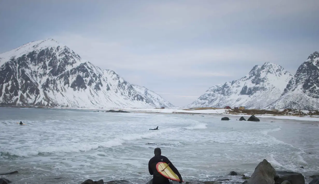 Seorang peselancar tengah bersiap untuk beraksi  di kawasan pantai  Flackstad, dekat Ramberg, kepulauan Lofoten, Arctic Circle, (10/3/2016). (AFP/Olivier Morin)